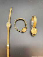 Three gold-tone ladies wristwatches laid out side by side