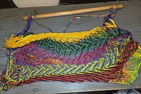 Rainbow rope chair hammock laid flat showing full net seat and wooden spreader bar