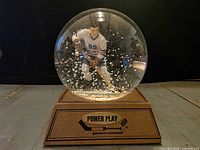 Front view of snow globe with hockey figure and flakes visible