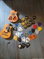 All picks and guitar-shaped case displayed on tabletop