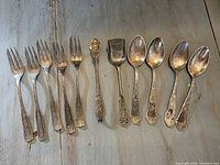 All eleven silver-tone flatware pieces laid out side by side