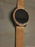 Front view of gold-tone round smartwatch highlighting black face and crystal bezel