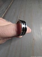 Ring on thumb showing exterior dual black grooves