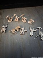 Group shot of nine unpainted metal Warhammer miniatures on tabletop