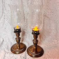 Pair of EPNS silver plated candlesticks with lit battery tea lights and etched glass chimneys