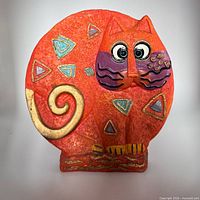 Front view of orange resin cat statue showing geometric accents and facial detail
