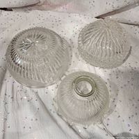 Three clear glass light shades showing overall condition and designs