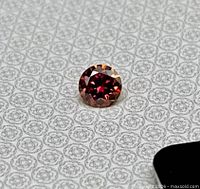 Close-up of round watermelon red moissanite on patterned background