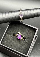 Both rings, silver-tone ring on mandrel, gold-tone ring in display box