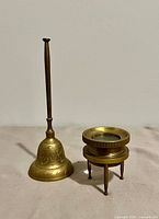 Brass hand bell and chart magnifier side by side