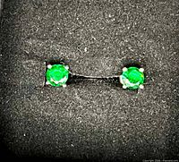 close-up of both stud earrings showing green stones and silver prongs