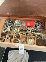 Full drawer view showing assorted hardware, pliers, wrench, grinding wheel and compartment trays