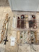 Overall view of lot showing necklaces, bracelets, earrings, brooches and pendants spread on floor and in clear organizer