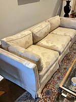 Front view of beige floral three-seat sofa with cushions