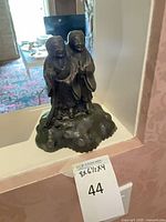 Front view of bronze sculpture showing two figures on rocky base