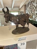 Full view of bronze donkey figurine on stand with measurement tag