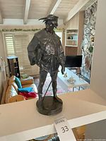 Front view of bronze standing male figure on circular base