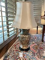 Full view of porcelain table lamp with shade on wood base