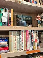 Books on shelves, blue ceramic vase and superhero figurine visible