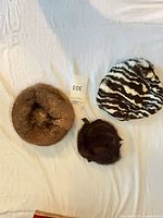 Overview of three vintage fur hats: light brown round hat, dark brown hat with bow, black and white striped cap