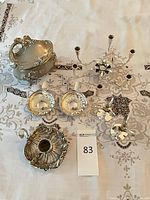 All eight silver plate pieces arranged on tablecloth