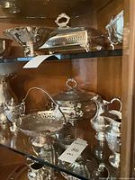 Multiple sterling silver serving pieces on display shelf