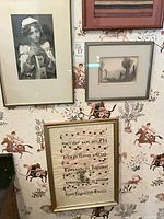 Overall view of the three framed artworks on wall: portrait photograph, landscape print, musical manuscript