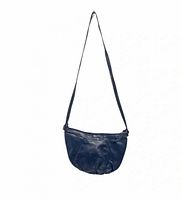 Full view of navy half-moon leather purse hanging, showing overall shape and strap length