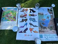 Wide shot of three posters laid on grass with cans holding corners