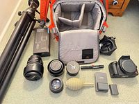 All items laid out: camera body, two Canon lenses, tripod, camera bag, boxed strap, air blower, charger, battery, memory card case, spare lens cap, pouch