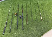 All six rods laid out on grass, two fitted with Penn Spinfisher V 6500 and Shimano Baitrunner 6000 OC spinning reels, remaining four rods shown in separate sections