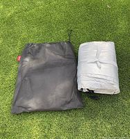 Folded Kayme car cover and black drawstring storage bag on grass