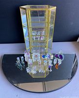 Curio cabinet and miniature animal figurines displayed on semicircular mirror base