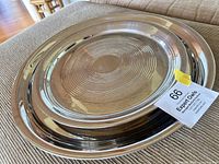 Two nested round stainless steel trays showing size difference