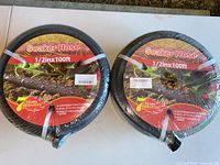 Two factory-wrapped soaker hoses showing labels with size and guarantee