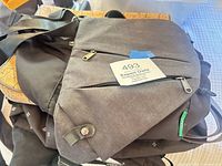 Pile of bags showing grey messenger, black bag underneath and cork tote corner visible