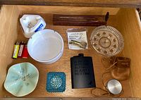 drawer view of ashtrays, flask, lighters, pouch, tin, pipe cleaners
