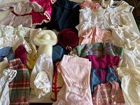 Overview of entire assortment of vintage doll clothes spread on table