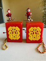 Front view of both Mattel Hurdy Gurdy toys showing ornate yellow plaques and monkeys