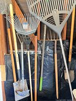 Group of rakes, shovels, hoe and spade hanging on wall