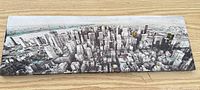 Full view of rectangular black & white city skyline canvas on wood surface