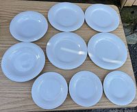 All nine white textured-rim plates and bowls laid out on table