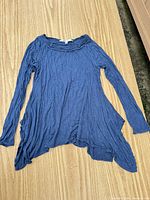 Full view of tunic laid flat showing color, sleeves and asymmetric hem