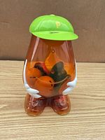 Front view of translucent Mr. Potato Head container showing cap, arms and internal parts