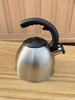 Front view of stainless steel kettle showing silver body, black handle and lid
