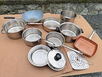 All cookware pieces laid out on cardboard