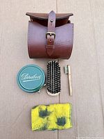 All items laid out: leather case, polish tin, large brush, small brush, cloth
