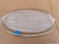 Full view of oval clear glass platter showing two embossed fish and overall condition