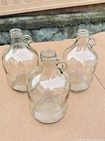 Three glass demijohn jugs viewed from above, showing loop handles and threaded necks