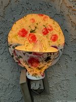 Front view of porcelain floral night light plugged in and illuminated